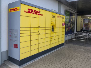 Lahde Almanya - 15 Nisan 2025: Bir mağazanın önünde bulunan DHL paket istasyonu paketler için modern bir self-servis teslimatı ve kamyonet çözümü sergiliyor.