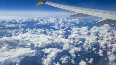 Pofuduk bulutların üzerinde, güneşli bir günde uçak kanadı. Manzara gökyüzünün enginliğini ve bulut oluşumlarının güzelliğini yakalıyor seyahat temalı projeler için mükemmel..