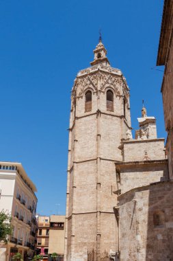 Valencia 'nın tarihi çan kulesi açık mavi gökyüzünün altında Gotik mimari ve kültürel simgeler sergileyen büyüleyici binalarla çevrili. Turizm için ideal..
