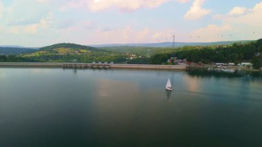 Solina barajının havadan görünüşü ve yeşil tepeler, durgun su gökyüzünü yansıtıyor..
