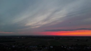 Gökyüzünde renkli bulutlar olan kırsal bir arazide dramatik bir günbatımının hava görüntüsü..