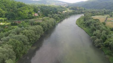 Yeşil vadileri ve küçük köyleri kesen kıvrımlı bir nehrin havadan görünüşü, tepelerle çevrili..