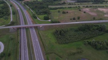 Yeşilliklerle çevrili bir otoyol üst geçidinin insansız hava aracı görüntüsü..