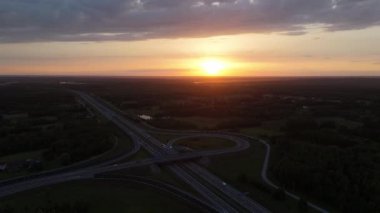 Gün batımında bir otoyol kavşağının hava görüntüleri yol ağının üzerindeki sıcak parıltıyı yakalıyor..