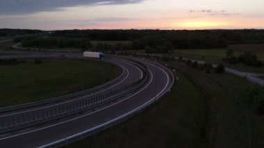 Alacakaranlıkta virajlı bir yolda seyreden bir kamyonun drone görüntüsü..