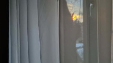 Karla kaplı tepelerin üzerinde kış günbatımının manzarası. Sıcak renkler gökyüzüne ve uzak tepelere yansıyor..