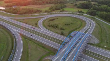 Otoyol kavşağının hava günbatımı görüntüsü kırsal kesimde seyahat, hareketlilik ve modern ulaşımı sembolize ediyor.
