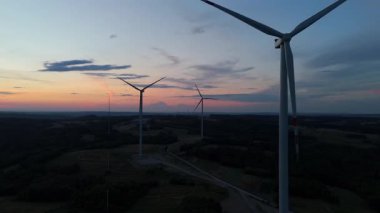 Alacakaranlıktaki çoklu rüzgar türbinlerinin hava görüntüsü, yenilenebilir rüzgar çiftliği kırsal alanda temiz elektrik üretiyor..