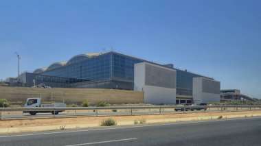 Alicante Spain - July 17 2025: Modern Alicante Airport building viewed from the road showcasing its unique architecture under a clear blue sky representing transportation hub essentials.