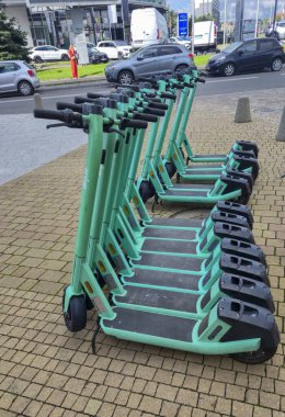 Rzeszow Poland - September 15 2025: A row of electric scooters parked on the sidewalk in a busy urban area showcasing eco-friendly transportation options.