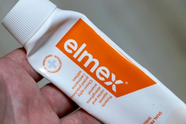 Warsaw Poland - September 24 2025: A close-up of a hand holding a tube of elmex toothpaste showcasing its dual action formula for preventing cavities and protecting gums.