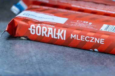 Warsaw Poland - September 24 2025: A close-up of Goralaki Mleczne candy wrappers showcasing their distinct red and white design against a metallic background.