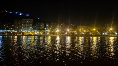 Night view of Alicante waterfront showcasing illuminated buildings and reflections on calm water creating a serene atmosphere perfect for travel and tourism.
