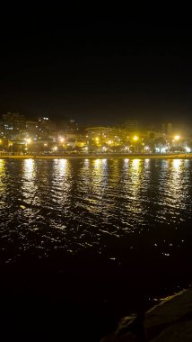 Alicante rıhtım manzarası sakin suya yansıyan canlı şehir ışıkları turizm ve rahatlama için ideal sakin bir atmosfer yaratıyor..