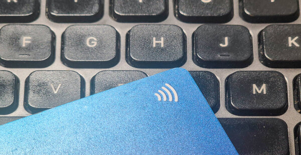 Warsaw Poland - September 24 2025: Close-up of a blue contactless payment card resting on a black keyboard showcasing modern technology in digital finance.