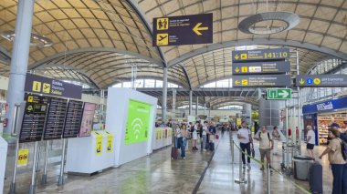 Alicante Spain - July 17 2025: Busy airport terminal showcasing travelers interacting with information screens and signage for departures and arrivals.