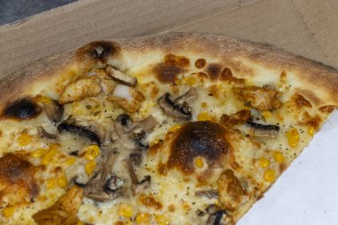 Delicious pizza with melted cheese mushrooms chicken and corn inside a cardboard box. Perfect for takeout or delivery meals during any time of the day.