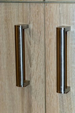 Ahşap çekmecelerde modern dolap tutacaklarının yakın plan tasarımı ve işçiliği. İç tasarım projeleri veya ev geliştirme temaları için ideal.