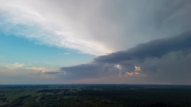 Uçsuz bucaksız bir arazide dramatik bir gökyüzü mavi ve gri renklerin bir karışımını sergiliyor. Bulutlar yeşil alanların üzerinde toplanıyor. Doğa ve havayla ilgili konular için mükemmel..