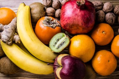 Image of persimmon, orange, banana, tangerine and other fruits on a wooden surface