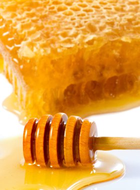 Organic Honey with wooden dipper against white. Image of honey in honeycombs closeup