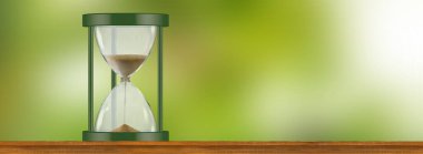 Yeşil çerçeveli bir kum saati, bulanık yeşil bir zemine karşı ahşap bir rafta duruyor..