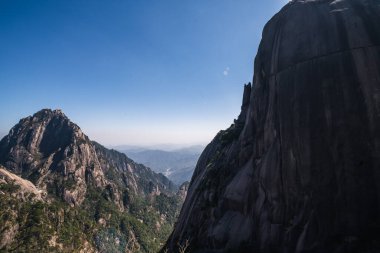 Huangshan sıradağlarının nefes kesici manzarası dramatik tepeleri, yemyeşil ormanları ve açık mavi gökyüzünü gözler önüne seriyor. Dağların katıksız büyüklüğü ve güzelliği doğanın ihtişamını yansıtıyor..