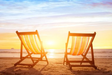Plaj turizmi, günbatımında bir çift şezlonglu tatil geçmişi.