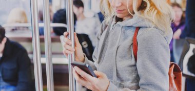 Metroda akıllı telefon ekranına bakan kişi, metroda cep telefonu tutan kadın.