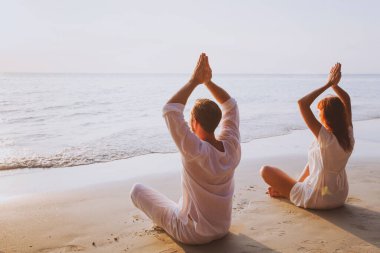 Grup meditasyonu, gün batımında plajda yoga.