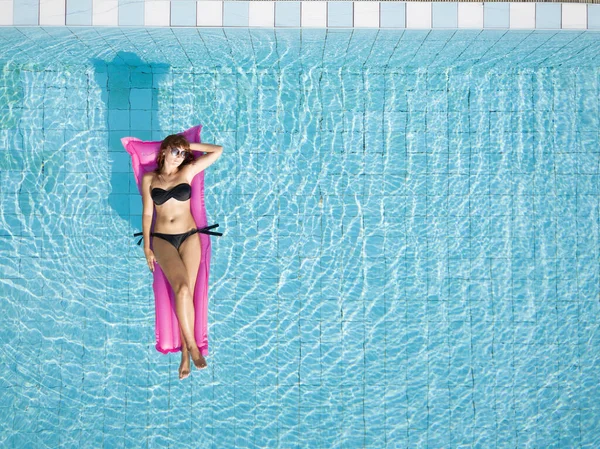 ビキニの女性は ホテルのスイミングプールで膨脹可能なマットレスでリラックスします ビーチ休暇 コピースペースと休日の背景 — ストック写真