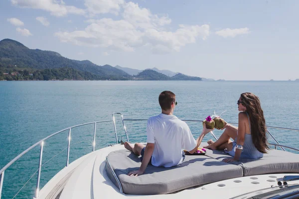 豪華なボートに乗って新婚旅行を楽しむカップル熱帯の海で豪華なヨット男と女ココナッツを飲んでリラックス — ストック写真