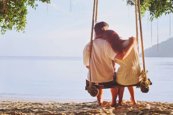 两人的浪漫假期 恋恋不舍的夫妻一起坐在沙滩上荡秋千 男人拥抱女人的轮廓 — 图库照片