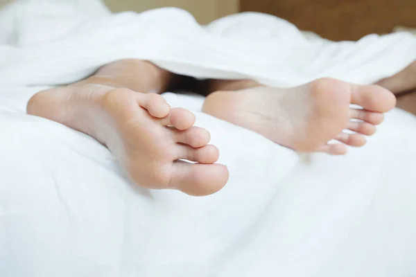 快適なマットレスの上の甘い睡眠 白い毛布の下のベッドの中の人の足 — ストック写真