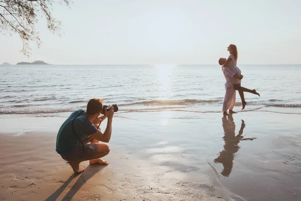 婚礼和生活方式摄影师在日落时在海滩上给深情的夫妻拍照 — 图库照片