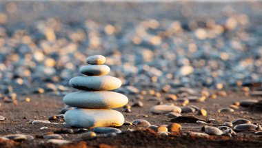 Kumsalda zen taşları, uyum ve barış dengesi, gün batımında meditasyon konsepti.