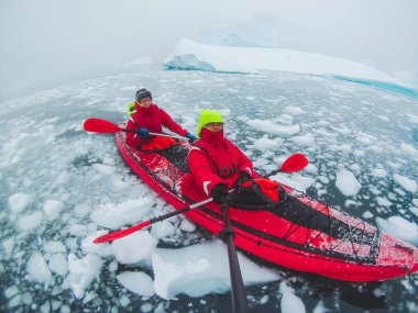 kayaking in Antarctica, couple of kayakers doing travel selfie with icebergs, extreme sport adventure honeymoon clipart