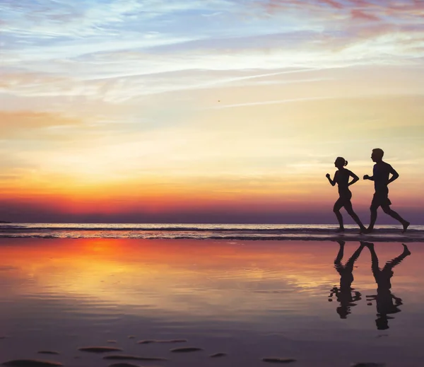 运动与健康 沙滩上的两个跑步者 日落时慢跑的人的轮廓 男女健康的生活方式 — 图库照片