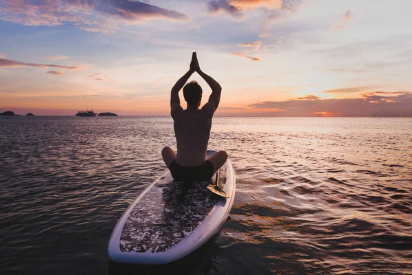 瑜珈在苏打水 男人的轮廓在荷花的位置站起来桨板上 — 图库照片