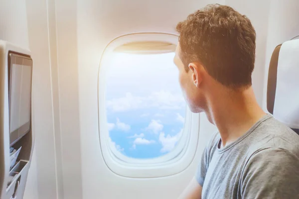 飞机上的乘客望着窗户 国际旅行 快乐的男子游客享受乘坐舒适的飞机飞行的乐趣 图库图片