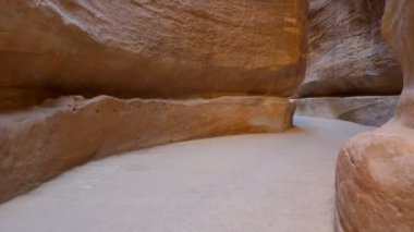 Siq 'te yürüyen turist, Ürdün' ün gizli şehri Petra 'ya giriş kapısı olarak hizmet veren dar taştan kanyon.