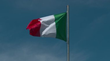 Avusturya ulusal bayrağı yavaş çekimde mavi bulutsuz gökyüzüne karşı dalgalanıyor.