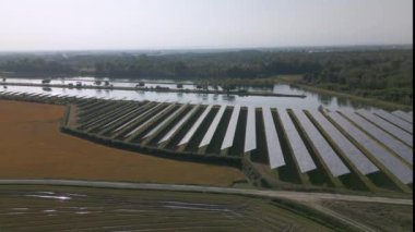 Temiz elektrik üretmek için birçok sıra fotovoltaik panele sahip güneş enerjisi santralinin havadan görünüşü. İtalya 'da sonbahar kırsalında.