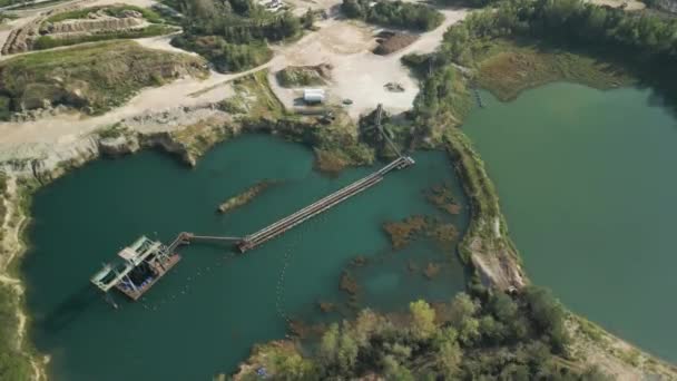 从空中俯瞰一个废弃的采石场 洪水的底部形成了一个绿水的湖泊 一种古老的采石机从水里冒了出来 — 图库视频影像