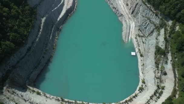 放棄された採石場の空中観察 浸水した底は緑の水を持つ湖を作ります 石抽出のための古い機械が水から現れる — ストック動画