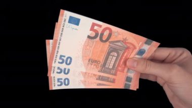 Bir adam ahşap zeminde tomar tomar para yakar. Enflasyon ve devrim kavramı, paranın değer kaybı, küresel kriz.