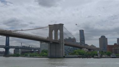 New York, Brooklyn Köprüsü. Bir feribot Doğu Nehri 'nde yol alırken, bir helikopter köprünün üzerinde süzülüyor..