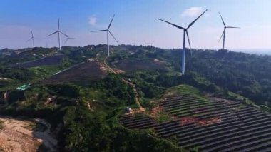 Kırsal kesimdeki güneş panelleri ve rüzgar türbinlerinin hava görüntüsü, yenilenebilir enerji kaynağı