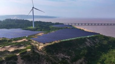 Kırsal kesimdeki güneş enerjisi panelleri ve rüzgar türbinlerinin günbatımı görüntüsü, yenilenebilir enerji kaynağı