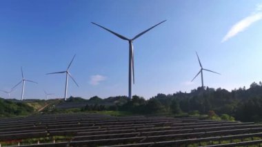 Kırsal kesimdeki güneş panelleri ve rüzgar türbinlerinin hava görüntüsü, yenilenebilir enerji kaynağı